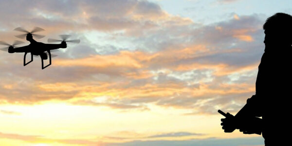 man operating of flying drone quadrocopter at sunset